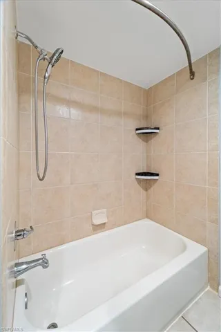 Bathroom featuring tile patterned flooring and tiled shower / bath combo