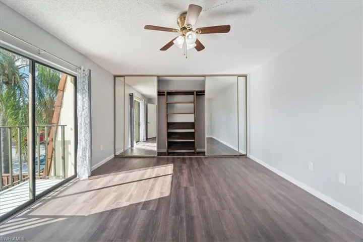 Unfurnished bedroom with a closet, ceiling fan, dark hardwood / wood-style flooring, and a textured ceiling
