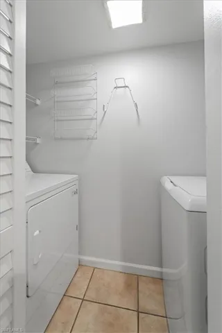Laundry room with washing machine and dryer and light tile patterned flooring