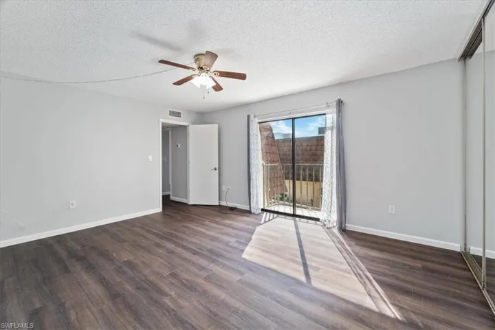 Spare room with ceiling fan, dark wood-type flooring, and a textured ceiling