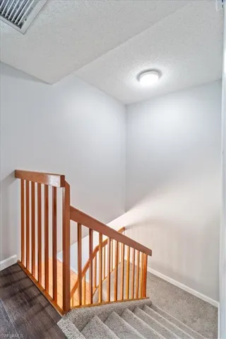 Stairway with carpet floors and a textured ceiling