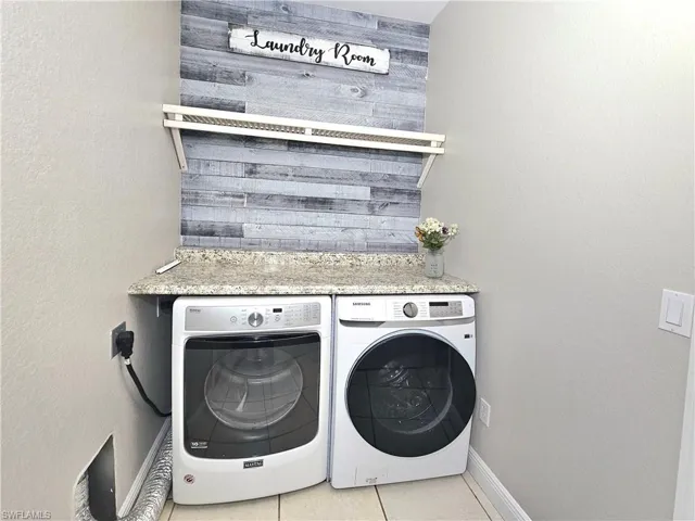 Laundry area featuring washer and clothes dryer and light tile patterned floors