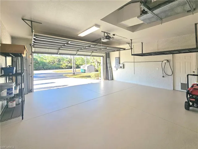 Garage featuring a garage door opener, electric panel, and a textured wall