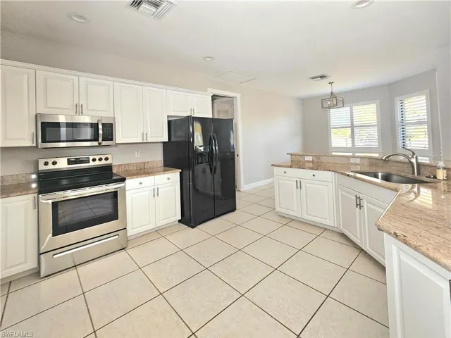 Kitchen with stainless steel appliances, a sink, white cabinetry, light tile patterned flooring, and recessed lighting