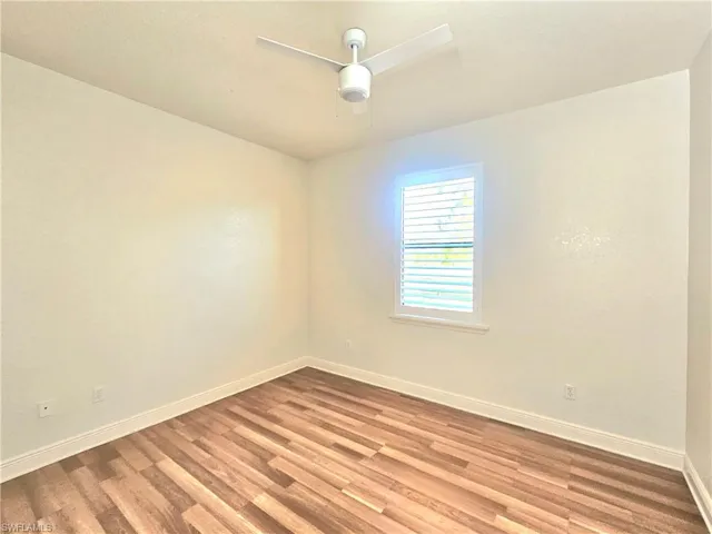 Unfurnished room featuring wood finished floors, ceiling fan, and baseboards