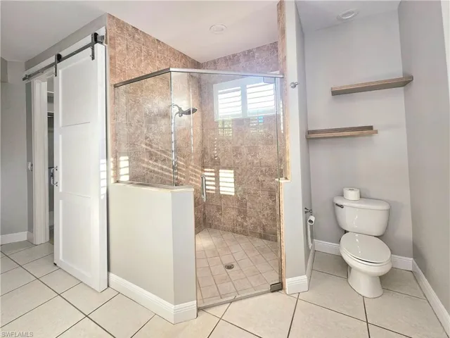 Bathroom with a shower stall, tile patterned flooring, toilet, and baseboards