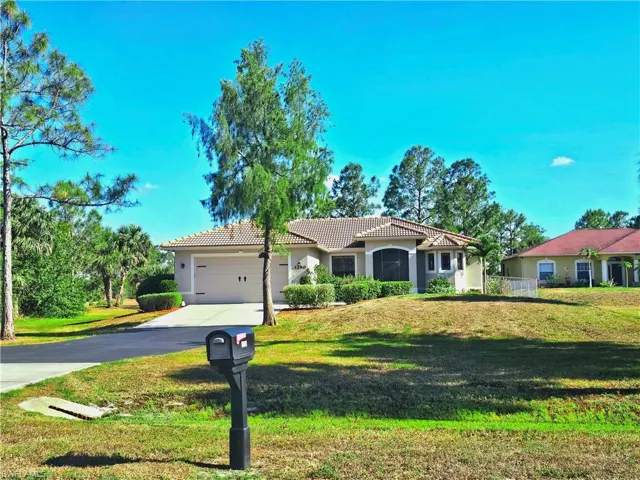 Mediterranean / spanish home with a tile roof, stucco siding, driveway, a garage, and a front lawn