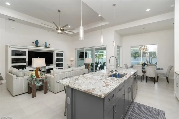 Kitchen featuring gray cabinets, light stone countertops, plenty of natural light, and sink
