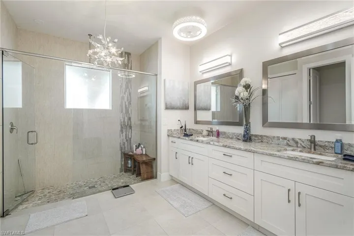 Master Bathroom with walk in shower, double sink vanity, tile patterned flooring, and designer lighting