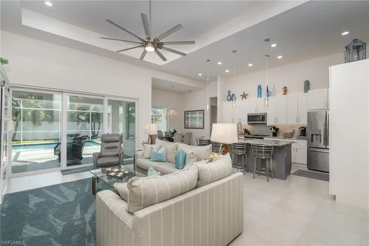 Living room featuring ceiling fan, light tile patterned flooring, and a tray ceiling