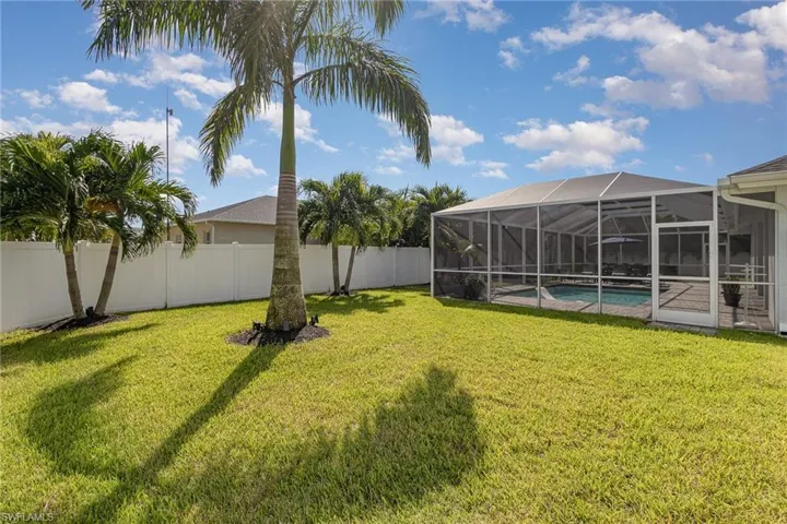 View of backyard with a privacy fence and inground pool and a screen enclosure.