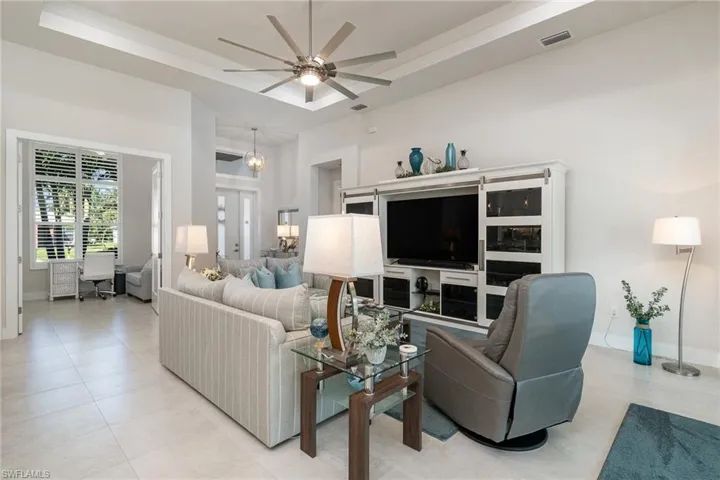 Tiled living room featuring a high ceiling, a tray ceiling, and ceiling fan