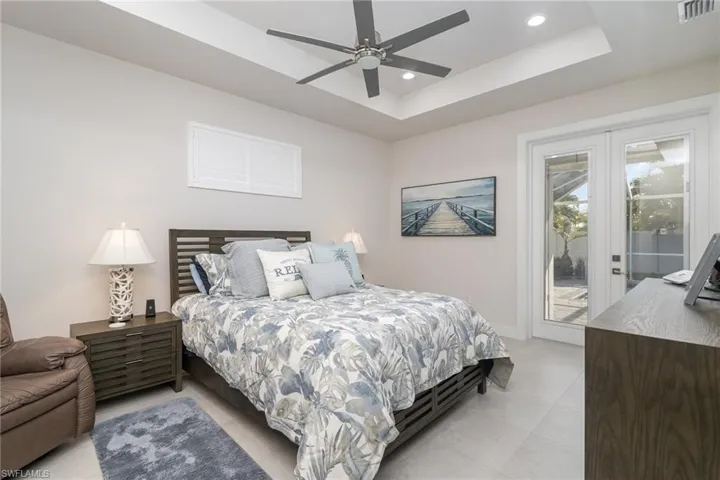 Master Bedroom with French door access to outside, a tray ceiling, and ceiling fan