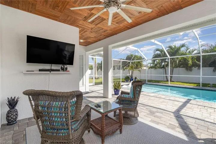View of lanai featuring wood ceiling, ceiling fan, a fenced in yard, pool with screen enclosure