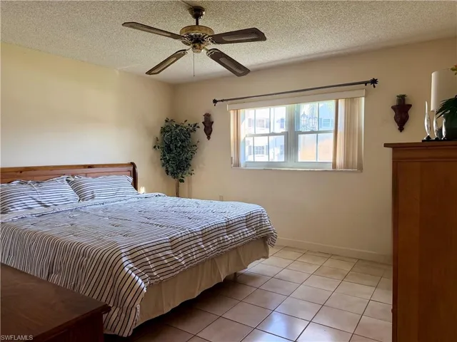 Primary Bedroom with walk-in closet, light tile flooring and ceiling fan