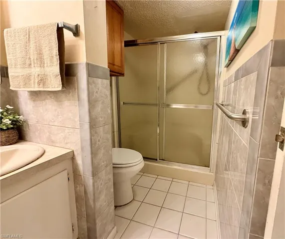 Full bathroom featuring vanity, standup shower and light tile flooring