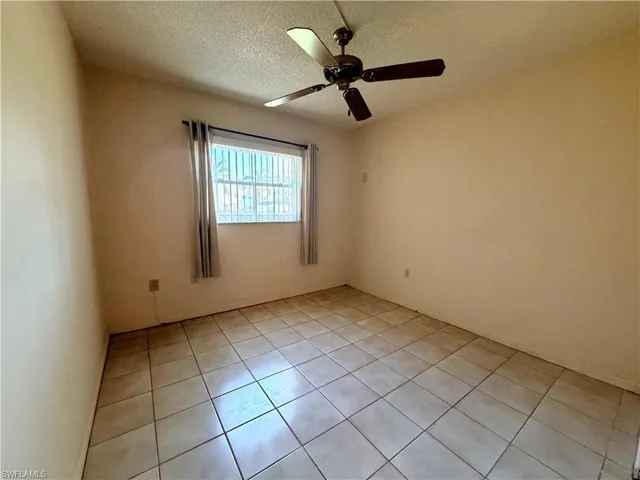 Second bedroom with  light tile floors and ceiling fan