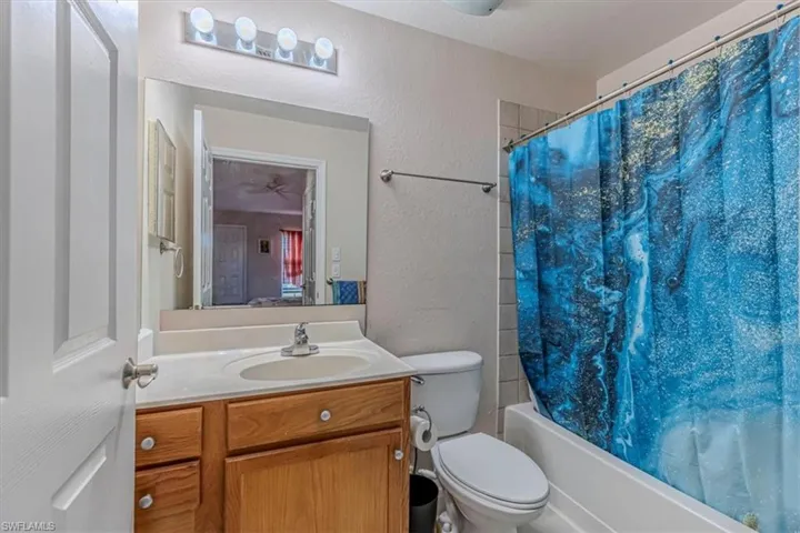 Bathroom featuring a textured wall, vanity, and shower / bath combo