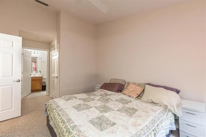 Bedroom featuring light carpet, ensuite bathroom, and a ceiling fan