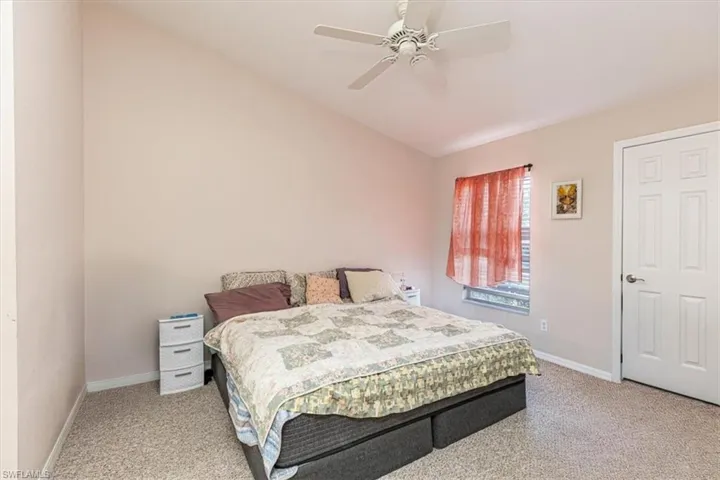 Bedroom with light carpet, ceiling fan, and vaulted ceiling