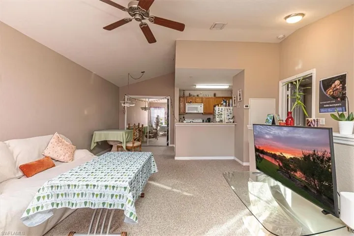 Bedroom with vaulted ceiling, light carpet, a closet, freestanding refrigerator, and a ceiling fan