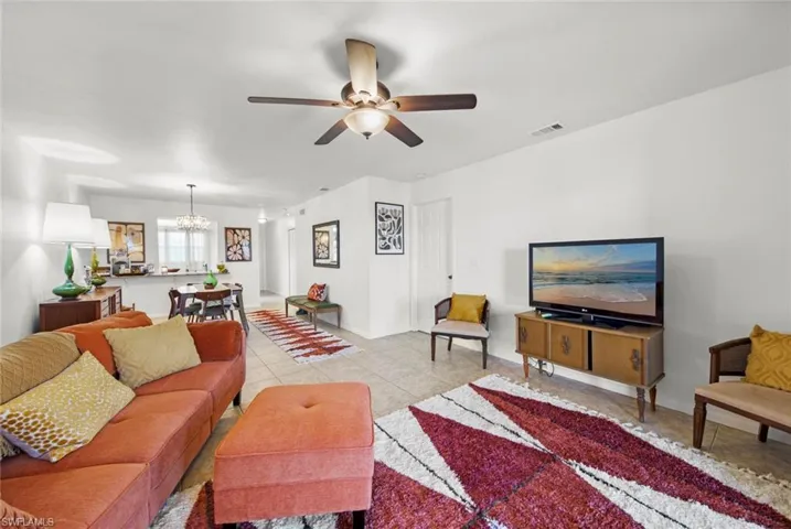 Living room featuring light tile patterned floors and ceiling fan with notable chandelier