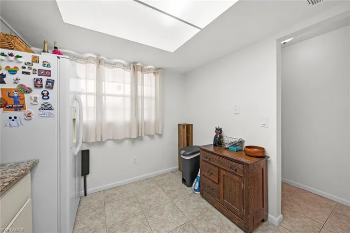 Kitchen featuring light tile patterned floors and white fridge with ice dispenser