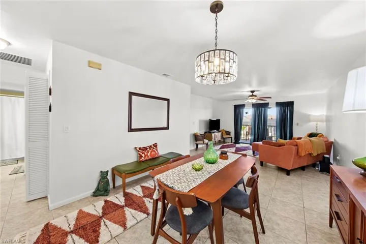 Tiled dining area featuring ceiling fan with notable chandelier