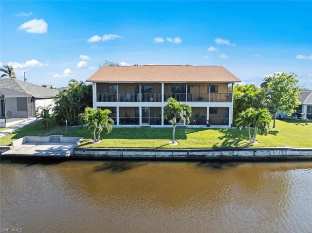 Back of house featuring a lawn and a water view