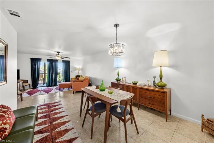 Tiled dining space with ceiling fan with notable chandelier