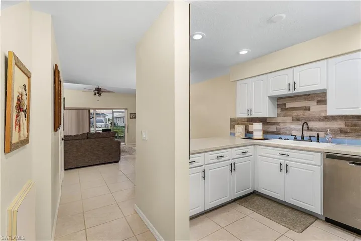 Kitchen featuring stainless steel dishwasher, light tile patterned flooring, white cabinetry, tasteful backsplash, and ceiling fan