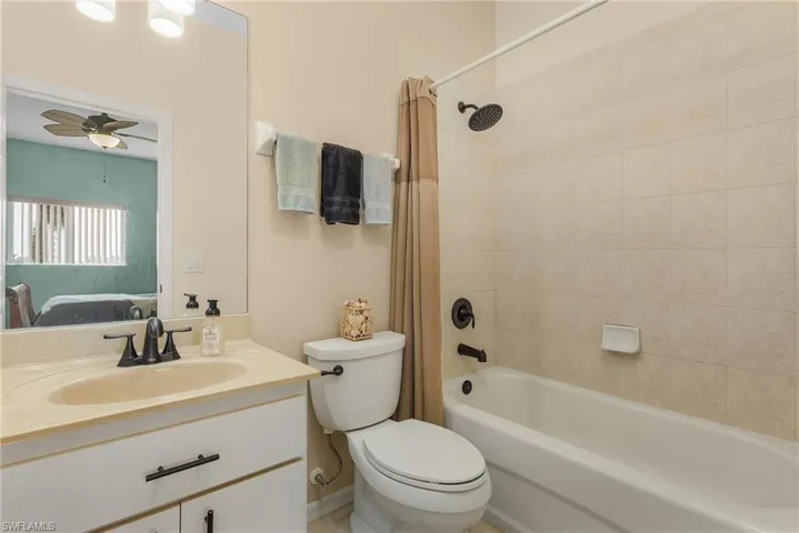 Full bathroom featuring shower / bath combo, toilet, vanity, and ceiling fan