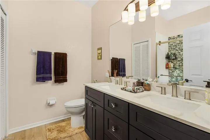 Bathroom with toilet, wood-type flooring, and double sink vanity