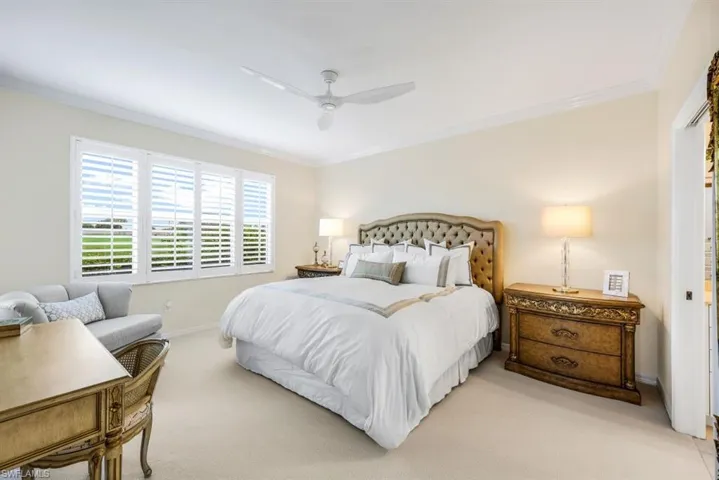 Bedroom featuring ceiling fan, ornamental molding, and light carpet
