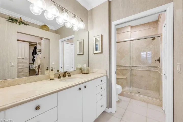 Bathroom with crown molding, toilet, an enclosed shower, tile patterned floors, and vanity