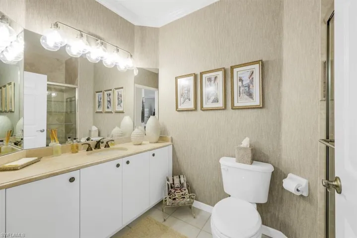 Bathroom featuring tile patterned floors, vanity, toilet, and crown molding