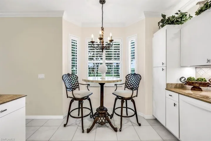 Tiled dining area featuring a notable chandelier and ornamental molding