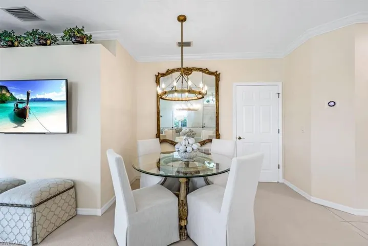 Carpeted dining area featuring a chandelier and ornamental molding