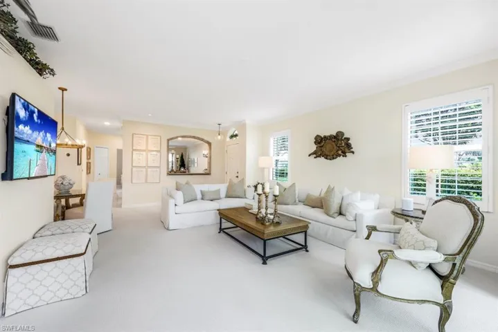 Living room featuring a healthy amount of sunlight, light colored carpet, and ornamental molding