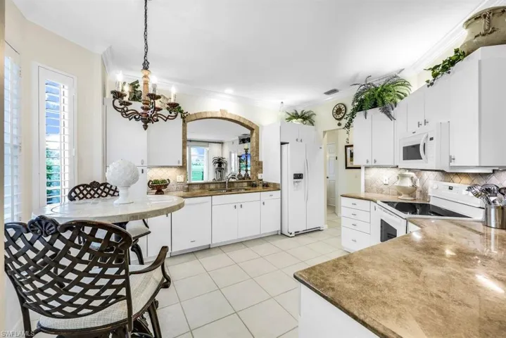 Kitchen with white cabinetry, sink, white appliances, and decorative backsplash