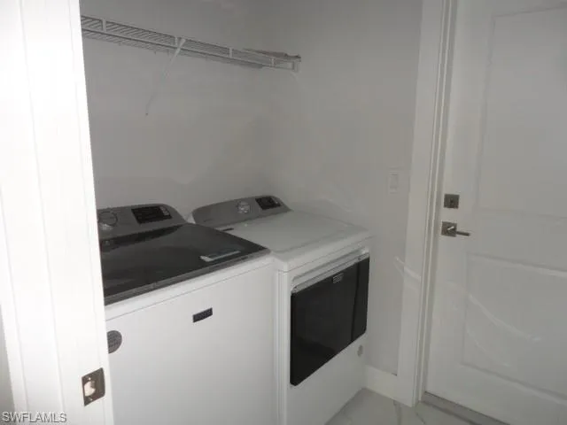 Laundry area with washer and dryer and light marble finish flooring