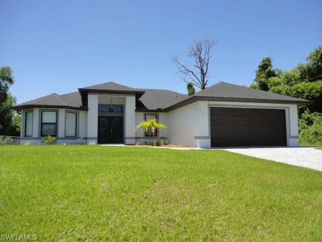 Prairie-style home featuring a garage, stucco siding, a front yard, and driveway