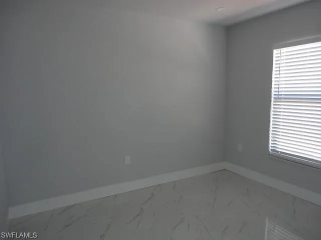 Spare room with baseboards, marble finish floors, and plenty of natural light