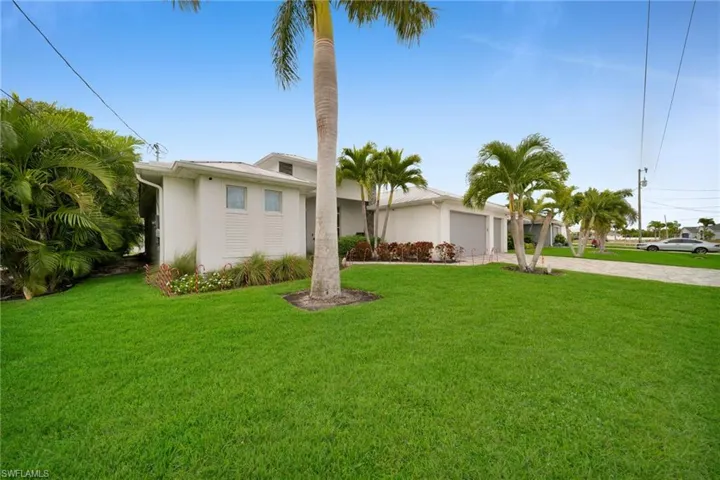 Mid-century modern home featuring decorative driveway, stucco siding, a front yard, and an attached garage