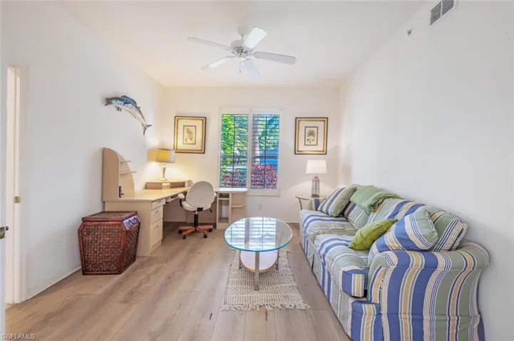 Living area with a desk, light wood finished floors, and a ceiling fan