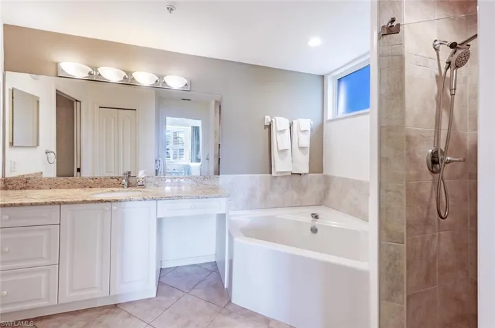 Bathroom with a bath, vanity, light tile patterned floors, and tiled shower