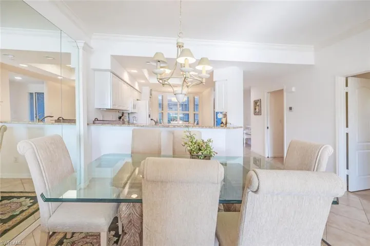 Dining room with light tile patterned floors, ornamental molding, and a chandelier