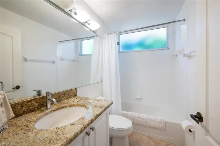 Bathroom featuring vanity, shower / bath combo, and light tile patterned flooring