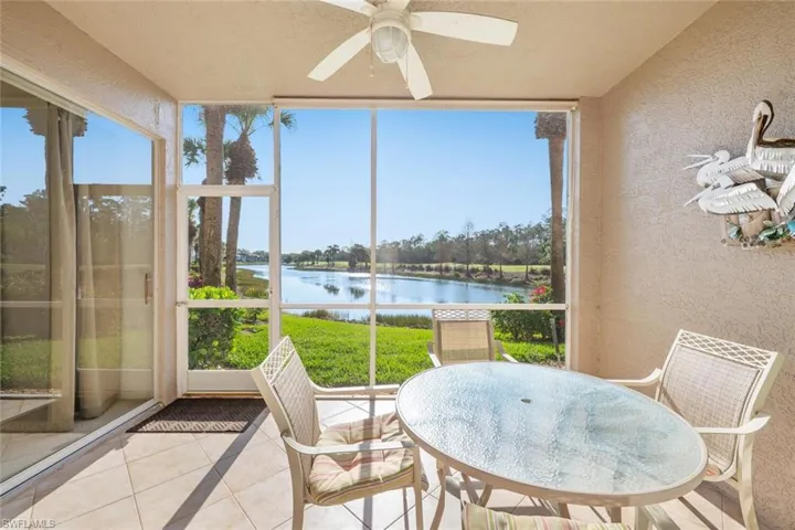 Sunroom featuring a textured wall, a water view, and tile patterned flooring