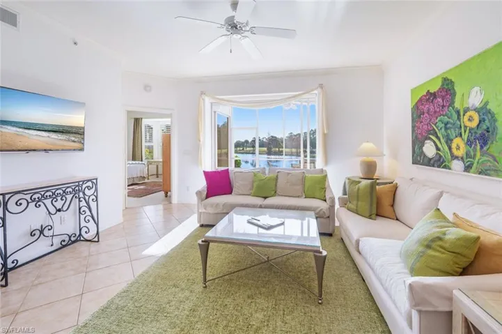 Living room with light tile patterned flooring, ornamental molding, a ceiling fan, and a water view